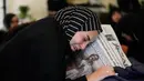 Zainab, saudara perempuan jurnalis Lebanon Amal Khalil yang tewas dalam serangan udara Israel pada Rabu 22 April 2026, memegang koran yang menampilkan potret saudara perempuannya, saat ia berduka di atas peti matinya di desa Baysariyeh, Lebanon Selatan, Kamis 23 April 2026. Jurnalis surat kabar Al-Akhbar, Amal Khalil, ditemukan meninggal dunia imbas serangan udara Israel di Kota al-Tayri, Lebanon Selatan pada Rabu 22 April 2026. (AP Photo/Mohammed Zaatari)