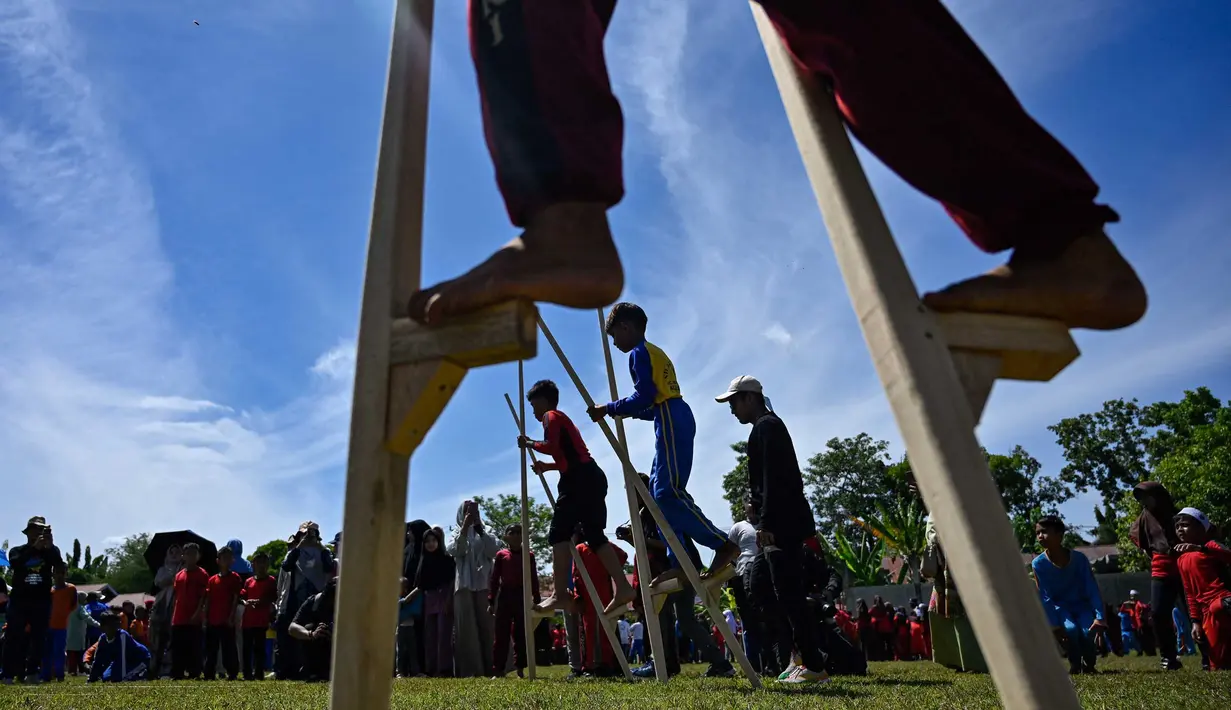 Siswa mengikuti permainan tradisional egrang pada Festival Permainan Tradisional Anak di Desa Wisata Lubok Sukon, Kecamatan Ingin Jaya, Aceh Besar, Aceh, Sabtu (25/7/2026). (AFP/ Chaideer Mahyuddin)