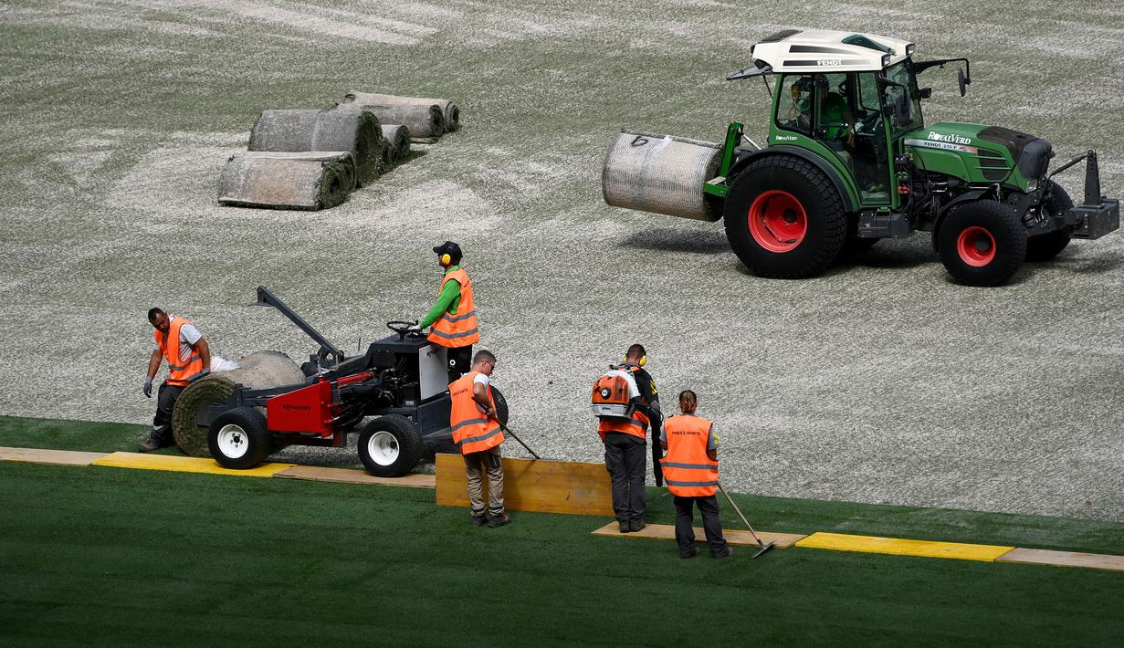 Sejumlah pekerja sedang memasang rumput hybrid baru di Stade de France, Saint-Denis, pada 24 Mei 2022 waktu setempat. Dalam waktu 48 jam, rumput baru yang ditanam di luar Barcelona, dipasang di Stade de France untuk pertandingan final Liga Champions antara Real Madrid dan Liverpool yang dijadwalkan berlangsung pada 28 Mei 2022. (AFP/Franck Fife)