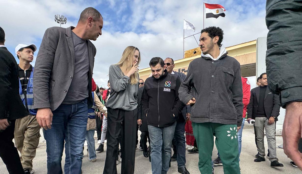 Dalam kunjungannya, Angelina Jolie sempat berbincang langsung dengan anggota Bulan Sabit Merah Mesir dan para sukarelawan serta pengemudi truk yang membawa bantuan kemanusiaan ke perbatasan. Tampak dalam foto, aktris Amerika Serikat (AS), Angelina Jolie (kedua kiri) saat tiba di perbatasan Rafah Mesir, pada Jumat 2 Januari 2026. (Foto oleh AFP)