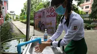 Seorang siswa yang mengenakan masker mencuci tangan di sekolah pada hari pendaftaran sekolah di Yangon, Myanmar (13/7/2020). Myanmar sejak Selasa (7/7) memulai pendaftaran sekolah untuk tahun ajaran 2020-2021, yang tertunda akibat pandemi COVID-19. (Xinhua/U Aung)