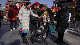 Keluarga mengunjungi shopping street pejalan kaki Qianmen pada hari pertama liburan Tahun Baru Imlek di Beijing, Minggu (22/1/2023). Orang-orang di seluruh China merayakan Tahun Baru Imlek pada hari Minggu dengan pertemuan keluarga besar dan kerumunan orang mengunjungi kuil-kuil setelah pemerintah mencabut kebijakan "nol-COVID" yang ketat, menandai perayaan meriah terbesar sejak pandemi dimulai tiga tahun lalu. (AP Photo/Andy Wong)