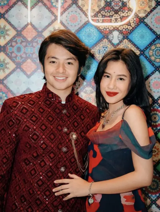 Shenina Cinnamon hadir dengan busana Bollywood didominasi warna biru dan merah. Sedangkan sang kekasih Angga dengan busana warna maroon lengkap dengan bros keemasan. [@snap.nuel]