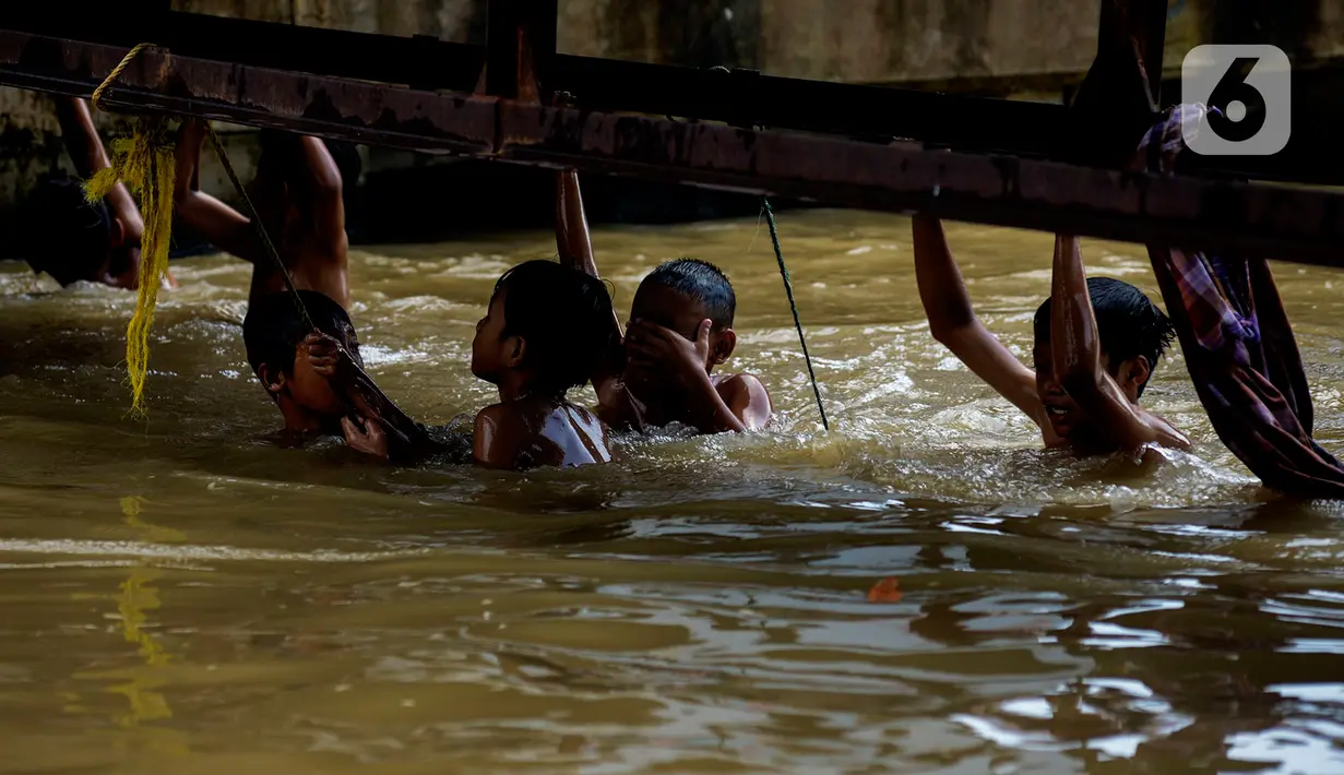 Sejumlah anak bermain dan berenang di aliran Kalimalang, Jakarta, Sabtu (15/2/2020). Cuaca yang tidak menentu membuat aliran air terkadang menjadi deras sehingga akan membahayakan keselamatan anak-anak saat bermain dan berenang. (merdeka.com/Imam Buhori)