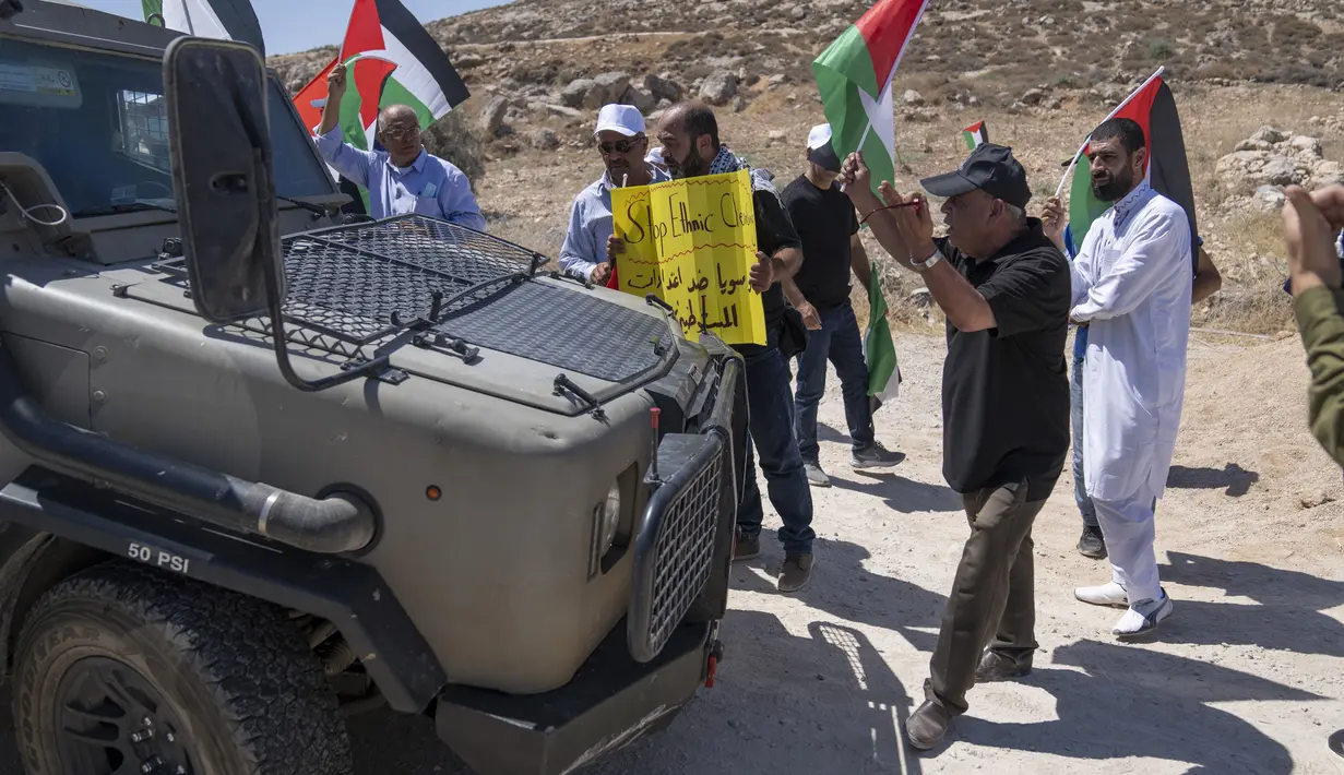 Pengunjuk rasa Palestina mengadang kendaraan tentara Israel saat mereka memblokir jalan yang melewati Desa Mughayer, Tepi Barat, utara Ramallah, 29 Juli 2022. Warga Palestina yang memprotes aktivitas permukiman Israel memblokir jalan utama dan bentrok dengan pemukim Israel, sementara tentara menembakkan gas air mata untuk membubarkan mereka. (AP Photo/Nasser Nasser)