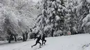 Anak-anak muda berlari menaiki bukit yang tertutup salju di sebuah taman di Ankara, Turki (26/12). AFP Photo/Adem Altan)