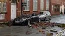 Reruntuhan atap apartemen yang runtuh karena angin kencang tampak berserakan dan menyebabkan sebuah mobil yang diparkir rusak parah di Leigh, barat laut Inggris, Rabu (18/11). (AFP PHOTO/Paul Ellis)