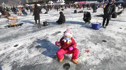 Seorang anak memancing ikan trout di sungai yang membeku di Hwacheon, Korea Selatan (6/1). Dalam lombo ini, peserta memancing ikan melalui lubang yang dibuat dipermukaan sungai yang membeku. (AP Photo/Ahn Young-joon)