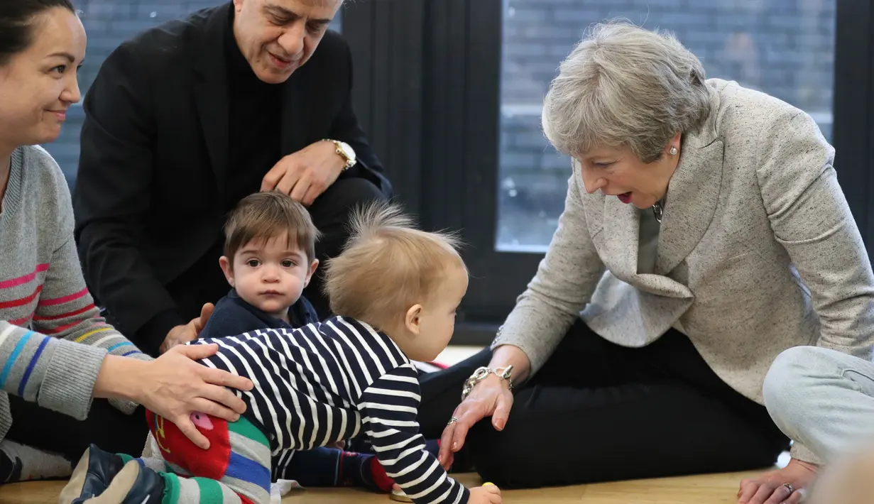Perdana Menteri Inggris Theresa May bermain dengan bayi saat berkunjung ke pusat kesehatan di London, Inggris, Kamis (22/11). Theresa menjabat sebagai Perdana Menteri Inggris sejak 2016. (Andrew Matthews/Pool via AP)