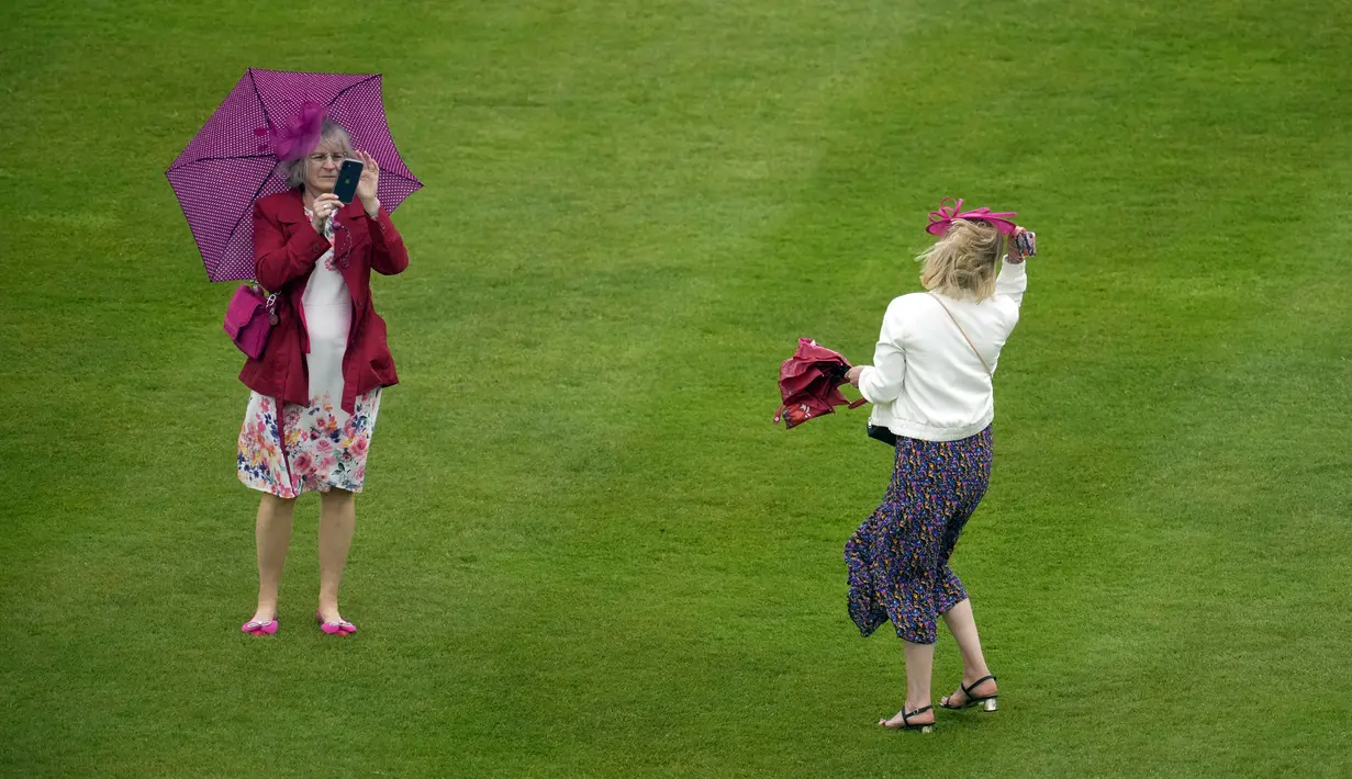 Para tamu menghadapi angin dan hujan saat mereka menghadiri pesta kebun pertama musim ini di Istana Buckingham, London, Inggris, 11 Mei 2022. Pesta kembali untuk pertama kalinya sejak 2019 setelah wabah virus corona COVID-19. (AP Photo/Matt Dunham, Pool)