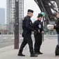 Polisi memeriksa dokumen warga saat lockdown di depan Menara Eiffel, Paris, Prancis, Rabu (18/3/2020). Prancis mengerahkan puluhan ribu polisi untuk berpatroli selama lockdown akibat virus corona COVID-19. (Ludovic MARIN/AFP)