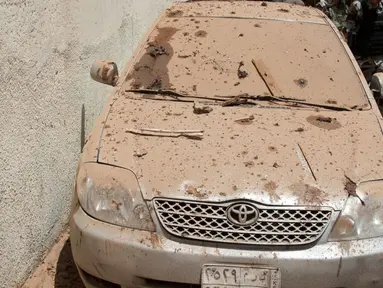 Sebuah mobil tertutup debu puing akibat ledakan bom bunuh diri di Mekkah, Arab Saudi (23/6). Sedikitnya 11 orang terluka akibat bom bunuh diri ini, lima di antaranya adalah anggota kepolisian. (Saudi Press Agency via AP)