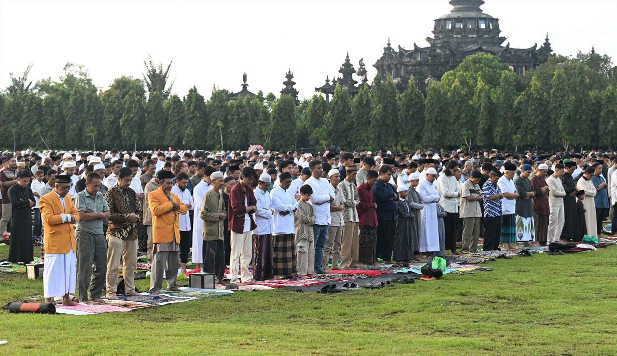 Pelaksanaan salat Idul Fitri berlangsung dengan khidmat di ribuan titik yang tersebar di berbagai wilayah, mulai dari lapangan terbuka hingga gedung-gedung dakwah. Tampak dalam foto, umat Muslim saat melaksanakan salat Idul Fitri 1447 Hijriah di monumen dan taman Bajra Sandhi di Denpasar, Bali, pada Jumat 20 Maret 2026. (SONNY TUMBELAKA/AFP)