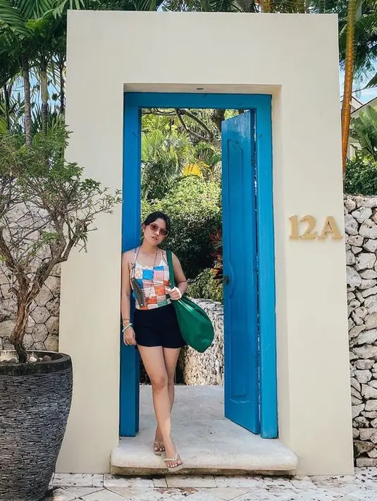 Marsha memilih memadukan atasan spaghetti strap motif kotak-kotak colorfull dengan celana pendek hitam dan tampak santai mengenakan sandal jepit dan tote bag besar hijau. [@aruanmarsha]
