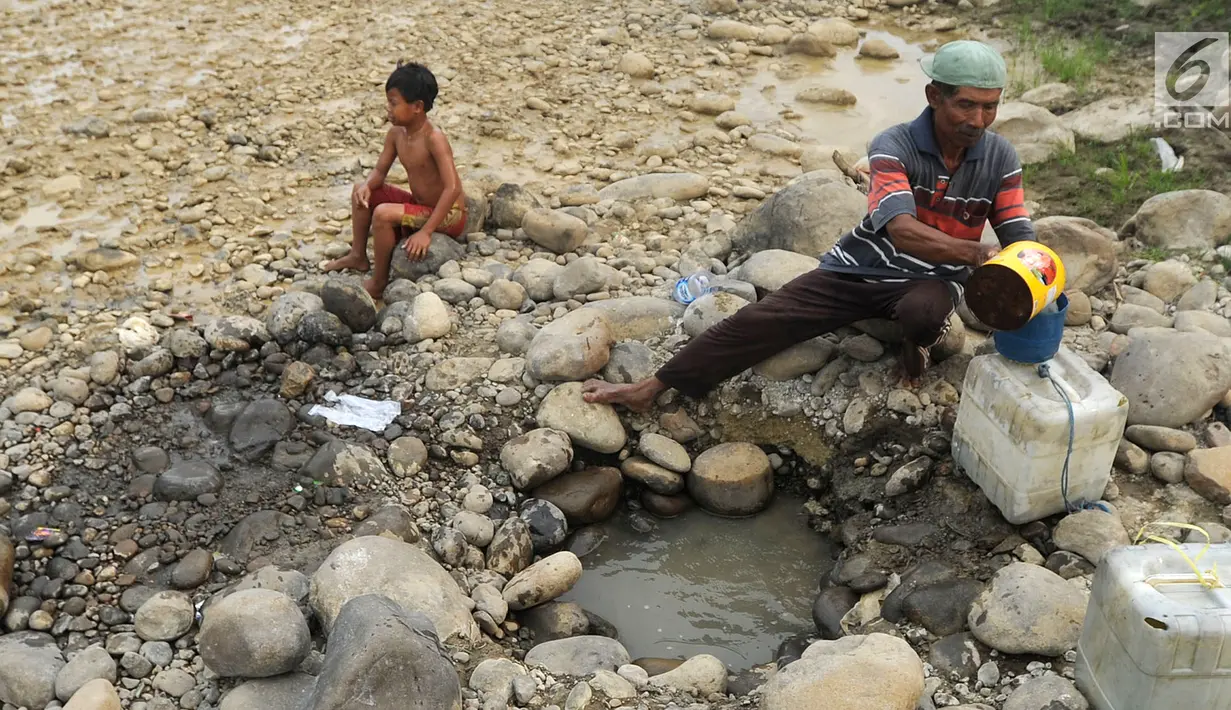 Warga mengambil air pada lubang di aliran Sungai Cipamingkis yang kering, Cibarusah, Bekasi, Jabar, Kamis (2/8). Dua bulan tak diguyur hujan menyebabkan warga perbatasan Bogor-Bekasi dilanda kekeringan dan kesulitan air bersih. (Merdeka.com/Arie Basuki)