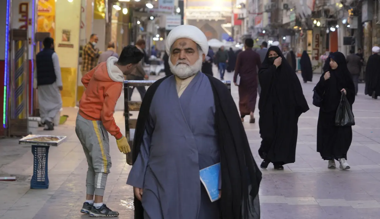 Seorang ulama Syiah berjalan di jalan di kota suci Najaf, Irak, 23 November 2021. Sekolah-sekolah agama di Irak kembali dibuka setelah lebih dari dua tahun di tengah pandemi COVID-19. (Qassem al-KAABI/AFP)