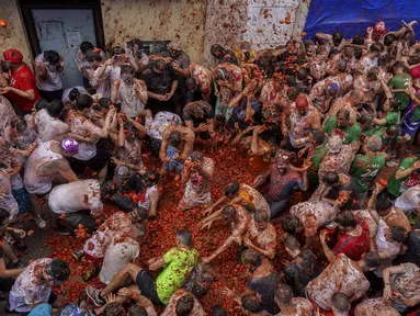 Orang-orang yang bersuka ria saling melempar tomat selama pesta pertarungan tomat tahunan "Tomatina", di desa Bunol dekat Valencia, Spanyol, Rabu (28/8/2024).  (AP Photo/Alberto Saiz)