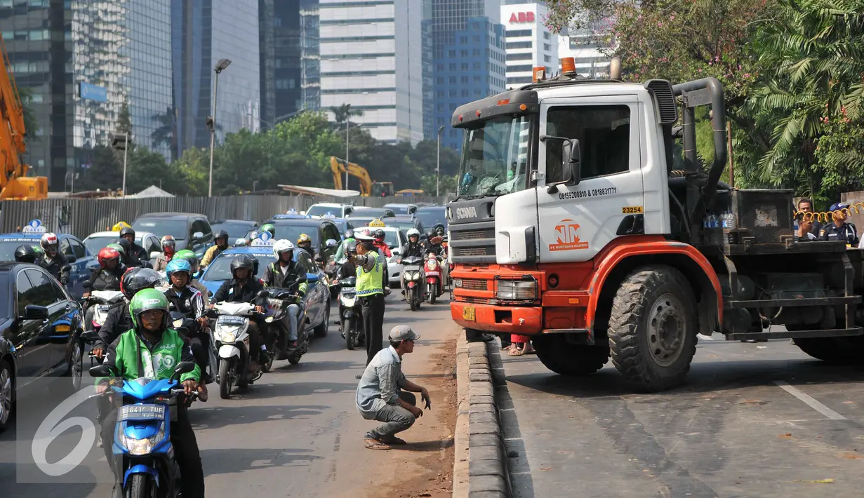 Petugas kepolisian mengatur lalu lintas akibat truk mengalami patah as di Jakarta, Selasa (29/9/2015). Imbas dari truk bermuatan alat berat mengalami patah as itu, Jalan Sudirman mengarah ke Jalan MH Thamrin terpantau padat. (Liputan6.com/Gempur M Surya)