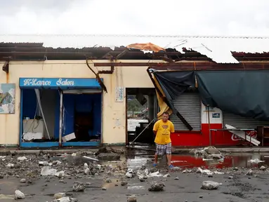 Seorang warga berjalan di depan sebuah bangunan yang rusak akibat Topan Nock-Ten di Mabini, Filipina (26/12). Topan super Nock-ten atau dikenal dengan Nina menerjang Filipina bertepatan saat Natal. (REUTERS/Erik De Castro)