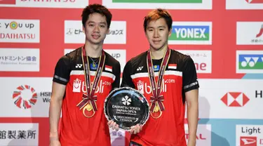 Ganda putra Kevin Sanjaya/Marcus Fernaldi Gideon berpose dengan trofi usai bertanding melawan  Hendra Setiawan / Mohammad Ahsan pada babak fina Jepang Terbuka 2019 di Tokyo (28/7/2019). Kevin / Marcus menang  21-19 dan 23-21.  (AFP Photo/Charly Triballeau)