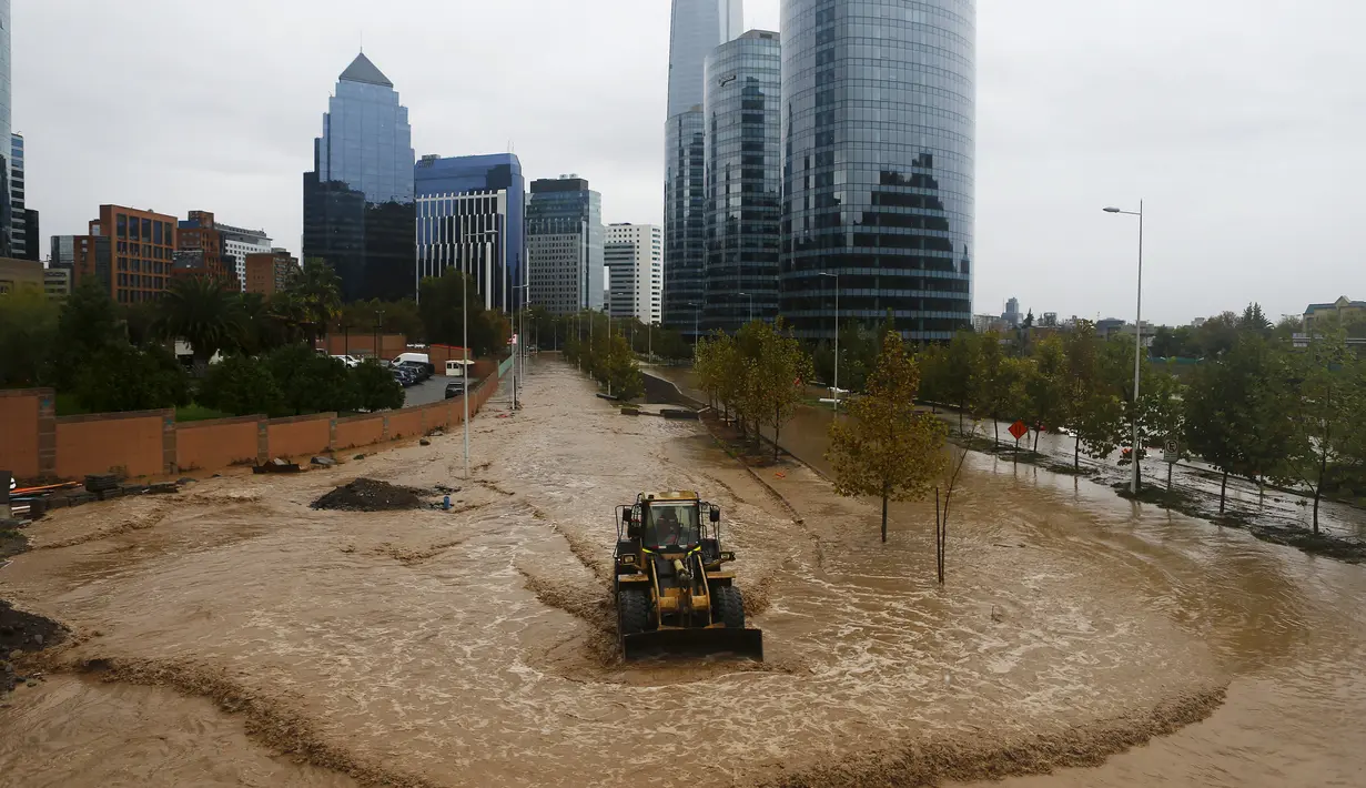 Sebuah loader menerjang banjir yang merendam jalan di Ibu Kota Chile, Santiago, Minggu (17/4). Hujan lebat dan parah di Ibu Kota Chile selama akhir pekan lalu menyebabkan 1 orang tewas dan 7 orang masih dinyatakan hilang. (REUTERS/Ivan Alvarado)