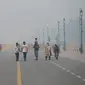 Pejalan kaki berjalan di sepanjang jalan dekat Gerbang India atau India Gate di tengah kabut asap tebal di New Delhi, Kamis (3/11/2022). Kabut asap di New Delhi mencapai tingkat hazardous (berbahaya) pada Kamis 3 November 2022. (Photo by Money SHARMA / AFP)