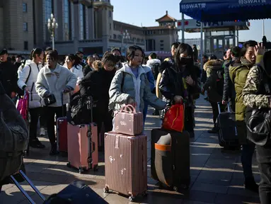 Calon pemudik menunggu kereta mereka di luar pintu masuk stasiun kereta api Beijing, Jumat (10/1/2020). Puluhan ribu warga China telah memulai migrasi manusia terbesar di dunia meninggalkan kota-kota besar menuju kampung halaman untuk merayakan Tahun Baru Imlek. (WANG ZHAO/AFP)