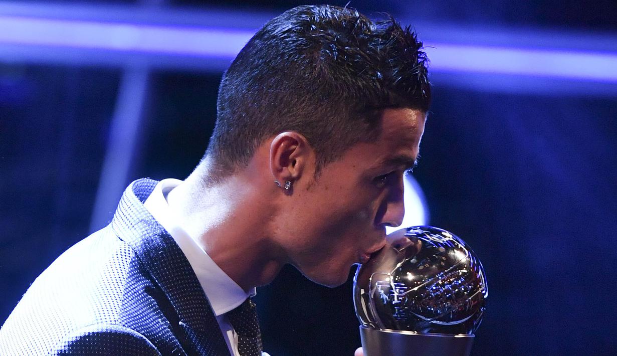Bintang Real Madrid, Cristiano Ronaldo, mencium trofi pemain terbaik FIFA 2017 di London, Senin (23/10/2017) Ronaldo berhasil mengalahkan Lionel Messi dan Neymar yang juga menjadi nominasi. (AFP/Ben Stansall)