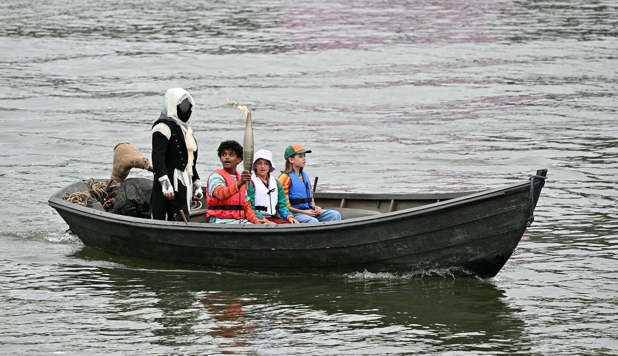 Sejumlah pemegang obor Olimpiade menaiki perahu saat upacara pembukaan Olimpiade Paris 2024, Prancis, 26 Juli 2024. (AFP/Miguel Medina)