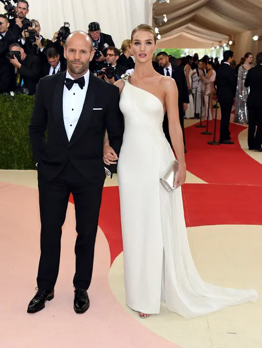 Kemesraan Jason Statham dan Rosie Huntington - Whiteley menghadiri ajang Met Gala 2016 di Metropolitan Museum of Art, New York City, Senin (2/5). Rosie tampak anggun dengan gaun menyentuh lantai dan Jason terlihat gagah memakai setelan jas. (AFP Photo)