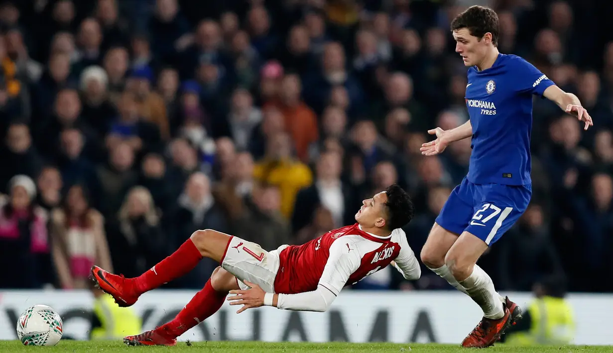 Pemain Arsenal Alexis Sanchez terjatuh di depan pemain Chelsea Andreas Christensen saat berebut bola pada laga semifinal pertama Piala Liga Inggris di Stadion Stamford Bridge, Rabu (10/1). Chelsea harus puas diimbangi Arsenal 0-0. (AP/Kirsty Wigglesworth)
