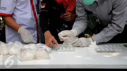 Petugas BNN melakukan uji lab lapangan barang bukti jenis sabu yang disita dari dua kelompok pengedar di Gedung BNN Jakarta, Kamis (29/10/2015). Sabu seberat 22,4 kg dimusnahkan BNN dihadapan sejumlah saksi dan tersangka. (Liputan6.com/Helmi Fithriansyah)