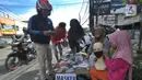 Seorang ibu ditemani anaknya melayani pembeli saat berjualan masker kain buatan rumahan di Jalan Raya Cinere-Depok, Limo, Depok, Rabu (8/4/2020).  Sebelumnya ia berjualan di pasar malam, namun semenjak larangan berjualan di pasar malam ia berjualan di pinggi jalan.  (merdeka.com/Arie Basuki)