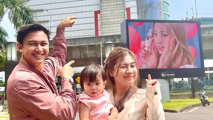 Felicya Angelista bersama suami dan anak berpose di videotron yang menampilkan TWICE sebagai duta Scarlett. (Foto: Dok. Koleksi Pribadi Felicya Angelista)