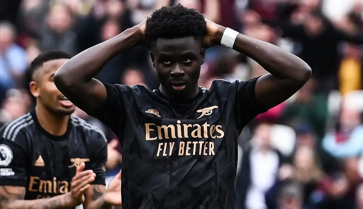 Reaksi kecewa gelandang Arsenal, Bukayo Saka setelah eksekusi penaltinya ke gawang West Ham United melebar dan gagal berbuah gol pada laga pekan ke-31 Liga Inggris 2022/2023 di London Stadium, London (17/4/2023). (AFP/Ben Stansall)