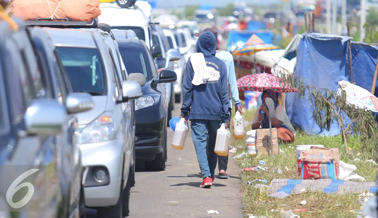 Warga menjual bensin kepada para pemudik yang mengantri di pintu tol Brebes Timur, Minggu (3/7). Warga menjual bensin dagangannya seharga perderigennya Rp 80 ribu. (Liputan6.com/Angga Yuniar)