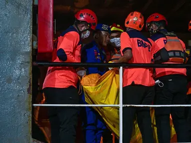 Sejumlah petugas mengangkat kantong berisi jenazah korban kebakaran KM Mutiara Sentosa II setibanya di Dermaga Jamrud Utara, Pelabuhan Tanjung Perak, Surabaya, Jawa Timur, Senin (3/8/2026). (AFP/ Juni Kriswanto)