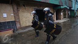 Dua polisi dengan tameng melakukan pengamanan di sekitar kawasan Kalijodo, Jakarta, Senin (29/2). Ribuan personel dari Polda Metro Jaya, TNI, Satpol PP dikerahkan untuk mengamankan penggusuran kawasan Kalijodo. (Liputan6.com/Immanuel Antonius)