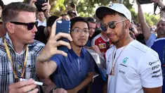 Pembalap Mercedes, Lewis Hamilton melakukan selfie dengan seorang penggemar menjelang sesi latihan bebas pertama di Grand Prix Australia, Melbourne, Jumat (24/3). (AFP Photo/WILLIAM WEST)