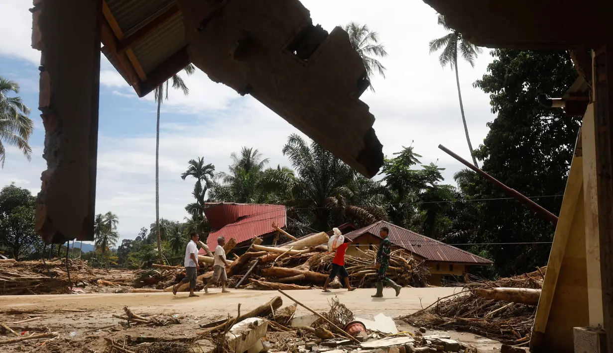 Hingga Selasa (2/12/2025) siang, kerusakan permukiman warga terlihat cukup parah, terutama yang berdekatan dengan Sungai Aek Garoga. Tampak dalam foto, warga berjalan melewati reruntuhan rumah di sebuah desa yang terdampak banjir di Batang Toru, Sumatra Utara, Rabu 3 Desember 2025. (AP Photo/Binsar Bakkara)