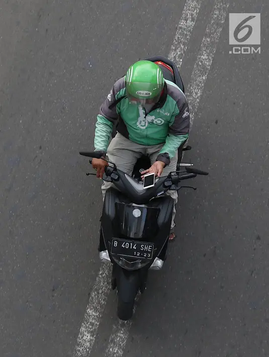 Pengendara sepeda motor mengoperasikan gawainya saat berkendara di Jakarta, Jumat (8/2). Polisi akan melakukan tindakan hukum berupa tilang kepada pengendara yang menggunakan GPS saat berkendara. (Liputan6.com/Immanuel Antonius)
