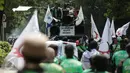Massa pengemudi ojek online menaiki mobil komando sambil berorasi saat unjuk rasa menuju Istana Negara, Jakarta, Senin (15/5). Aksi tersebut menuntut adanya perbaikan pemberlakuan tarif dasar yang dirasa merugikan pengemudi. (Liputan6.com/Faizal Fanani)