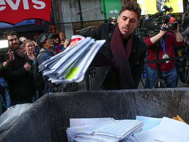 Seorang pria melempar kertas berisi kenangan menyulitkan ke tempat sampah selama kegiatan Good Riddance Day ke-13 tahunan di Times Square, New York, 28 Desember 2019. Kegiatan menjelang tahun baru tersebut menjadi tradisi untuk menghapus kenangan buruk selama satu tahun. (Kena Betancur / AFP)