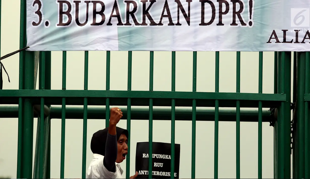 Seorang wanita berdiri di depan pagar Gedung DPR saat aksi unjuk rasa yang berlangsung pada Rabu (12/7). Dalam aksinya mereka menuntut Rampungkan RUU Anti - Terorisme, Tolak Hak Angket KPK, dan Bubarkan DPR. (Liputan6.com/Johan Tallo)