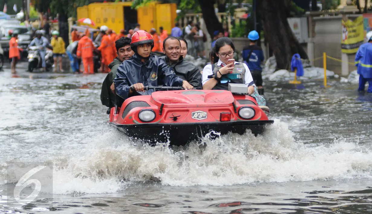  Warga dan pelajar dibantu mobil amfibi melewati genangan air di depan kampus UKRIDA, Jakarta, Selasa (21/1). Hujan deras sejak malam tadi, membuat sejumlah wilayah Jakarta tergenang air banjir. (Liputan6.com/Gempur M Surya)