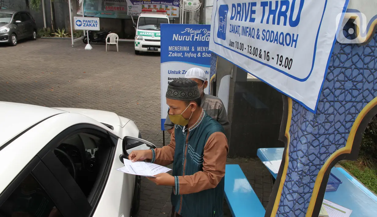 Petugas Amil Zakat melayani warga yang membayar zakat fitrah melalui sistem "drive thru" di Masjid Nurul Hidayah, Tanah Kusir, Jakarta, Selasa (19/5/2020). Layanan zakat "drive thru" selama pandemi COVID-19 ini diberlakukan dengan protokol kesehatan dan keselamatan. (Liputan6.com/ Johan Tallo)