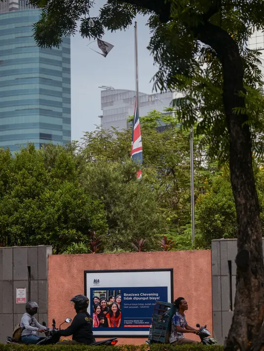 Pengendara mobil melewati kedutaan Inggris dengan bendera Inggris setengah tiang setelah kematian Ratu Elizabeth II, di Jakarta pada 9 September 2022. Para anggota keluarga kerajaan, sempat mendampingi sang ratu, saat kondisi kesehatannya memburuk. (Photo by BAY ISMOYO / AFP)