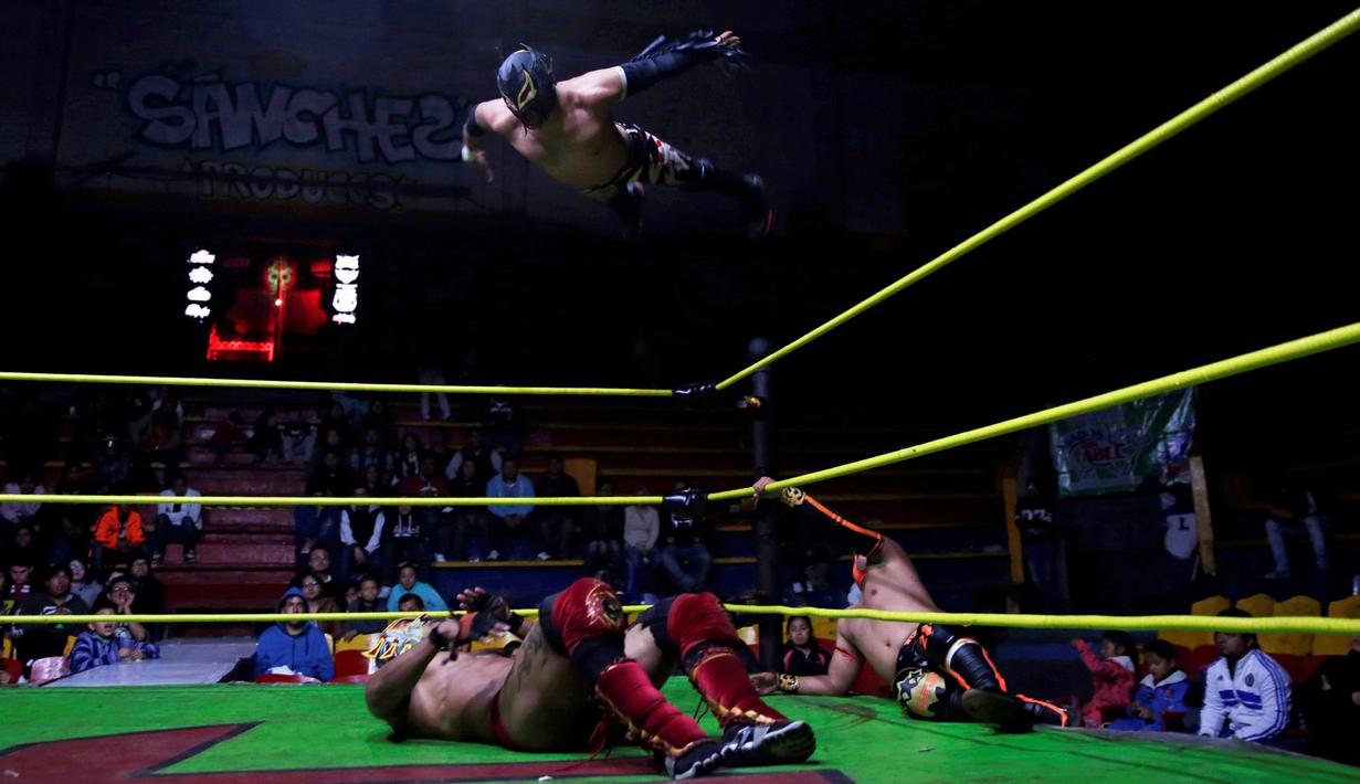 Seorang penggulat yang dikenal Aero Boy melompat menyerang lawannya, Dragon Rojo Jr yang terbaring di atas ring saat pertandingan gulat di Arena Neza di pinggiran Mexico City, Meksiko (28/10). (Reuters/ Carlos Jasso)