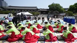 Wanita dan pria mengenakan gaun tradisional Korea Selatan membungkuk selama upacara untuk menghidupkan kembali Hari Kedewasaan ke-50 di Desa Hanok Namsangol di Seoul, Korea Selatan (16/5/2022). Upacara diadakan untuk pria dan wanita muda yang akan berusia 20 tahun. (AP Photo/Lee Jin-man)
