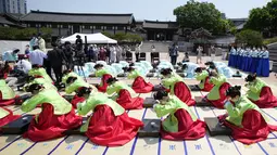 Wanita dan pria mengenakan gaun tradisional Korea Selatan membungkuk selama upacara untuk menghidupkan kembali Hari Kedewasaan ke-50 di Desa Hanok Namsangol di Seoul, Korea Selatan (16/5/2022). Upacara diadakan untuk pria dan wanita muda yang akan berusia 20 tahun. (AP Photo/Lee Jin-man)